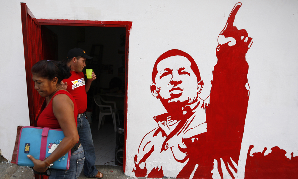 A woman leaves a campaign office of United Socialist Party of Venezuela (PSUV) with a painting of President Hugo Chavez in the neighborhood of Petare in Caracas November 12, 2008. Venezuelans go to the polls on Nov. 23 to elect state governors and city mayors. REUTERS/Jorge Silva (VENEZUELA)